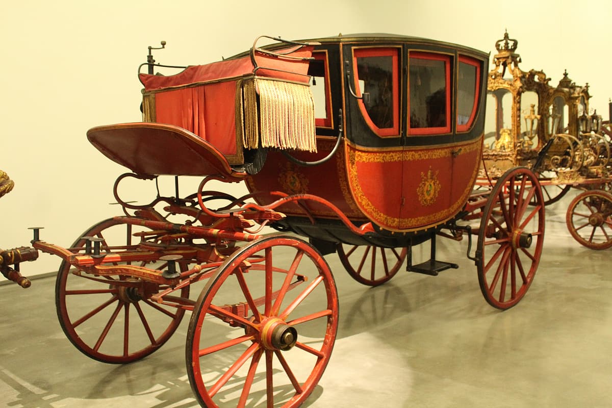 A gala coach in the Museu Nacional dos Coches, Lisbon, with the gilded gold state coaches of the Portuguese royal collection behind it.